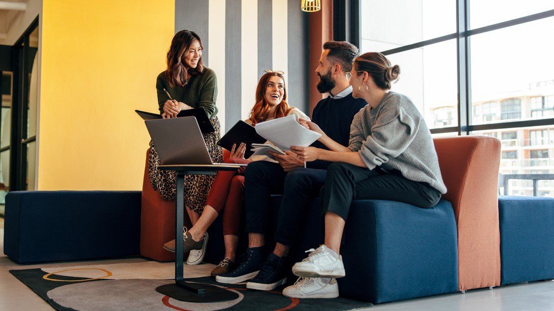 Multicultural businesspeople working in an office lobby. Group of happy businesspeople smiling while sitting together in a co-working space. Young entrepreneurs collaborating on a new project. CPA program career paths.