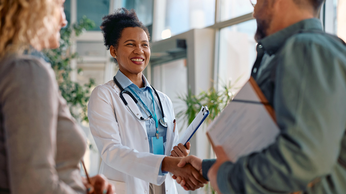 Doctor shaking hands with a client in a medical office, representing the sale or transition of a professional practice.